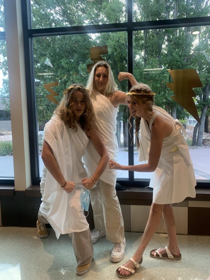 Juniors Jessie Duytschaever, Cameron McKerlie, and Marcella Bee flex their best togas for Toga Day in Zeus hallway under the lightning bolts, exerting their strength together. Photo Credit: Chris Moody
