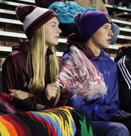 Seniors Kate Twede and Cedar Collins huddle together for warmth under the cold sleet of the stadium, watching the game with intensity.
Photo Credit: Chris Moody